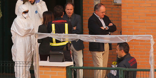 Firemen stand as worker wearing rompers and gloves come out ofthe building entrance of the apartment building of the Spanish nurse infected with Ebola in Madrid, Spain, Wednesday, Oct. 8, 2014. (AP Photo/Andres Kudacki)