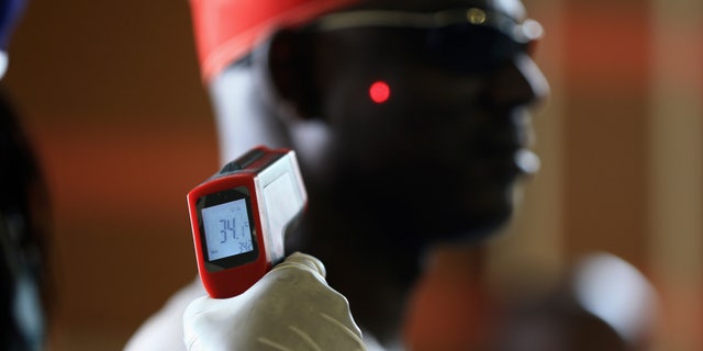 A man has his temperature taken using an infrared digital laser thermometer at the Nnamdi Azikiwe International Airport in Abuja, August 11, 2014. (REUTERS/Afolabi Sotunde)