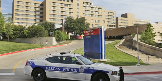 A police car drives past the entrance to the Texas Health Presbyterian Hospital in Dallas, Tuesday, Sept. 30, 2014. (AP Photo/LM Otero)