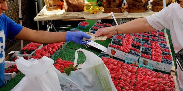 In this Friday, Feb. 6, 2015 photo, a shopper pays for produce at a Farmers Market in downtown Los Angeles. The Commerce Department releases its January report on consumer spending, which accounts for 70 percent of economic activity, on Monday, March 2, 2015. (AP Photo/Richard Vogel)