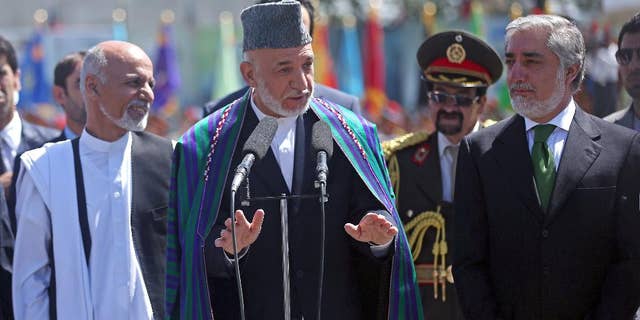 Afghan President Hamid Karzai, center, speaks in  front of local and international media representatives as presidential candidates Abdullah Abdullah, right, and Ashraf Ghani Ahmadzai, left , listen during the Independence Day ceremony in Kabul, Afghanistan, Tuesday, Aug. 19, 2014. King Amanullah won the country's independency from Britain in 1919. (AP Photo/Massoud Hossaini)