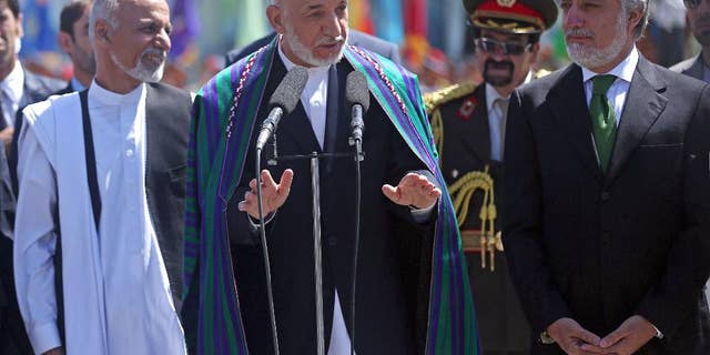 Afghan President Hamid Karzai, center, speaks in front of local and international media representatives as presidential candidates Abdullah Abdullah, right, and Ashraf Ghani Ahmadzai, left , listen during the Independence Day ceremony in Kabul, Afghanistan, Tuesday, Aug. 19, 2014. King Amanullah won the country's independency from Britain in 1919. (AP Photo/Massoud Hossaini)