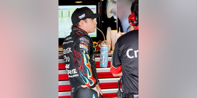Driver Jeff Gordon drinks from a water bottle as he talks with his crew in the garage area during practice, Friday May 10, 2013, in Darlington, S.C., for Saturday's NASCAR Sprint Cup series auto race. (AP Photo/Mic Smith)