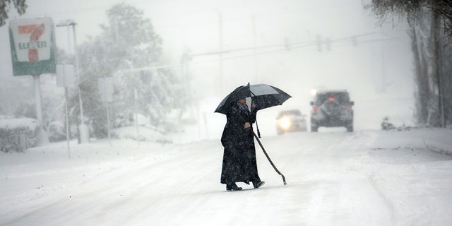 A person tries to cross an icy Pleasure House Rd. in Virginia Beach, Va., during the storm Thursday. Virginia has been socked by a powerful winter blast of snow and cold that's seldom seen along its coast.