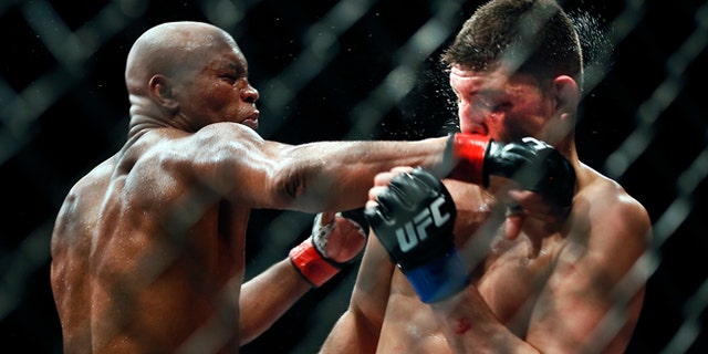 Middleweight Anderson Silva draws a fist across the face of Nick Diaz during their fight at the MGM Grand Garden Arena in Las Vegas on Saturday, Jan. 31, 2015. (AP Photo/Las Vegas Sun/LE Baskow)