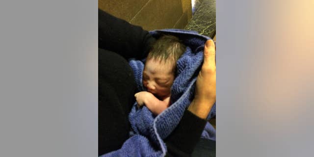 In this Monday, Nov. 23, 2015 photo provided by Paul Cerni, an unidentified woman holds a baby at the Holy Child of Jesus Church in the Richmond Hill section of Queens, New York. A church custodian found the abandoned newborn Monday in the church nativity scene. New York has a so-called safe haven law that says a newborn can be dropped off anonymously at a church, hospital, police or fire station without fear of prosecution. But the law, known as the Abandoned Infant Protection Act, requires that the child be left with someone or for authorities to be called immediately. Police are searching for the mother. (Paul Cerni via AP)