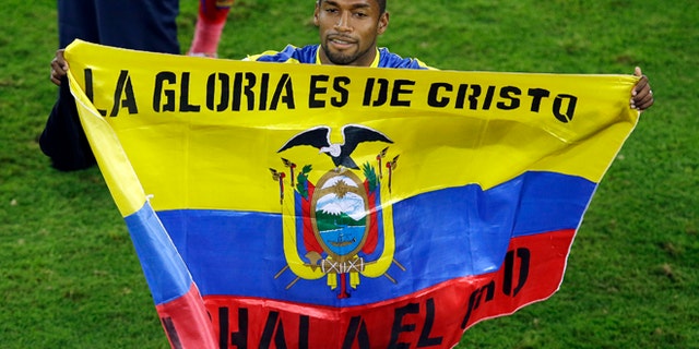 June 20, 2014: Ecuador's Gabriel Achilier holds a Ecudorian flag with the writing 'The glory is for Christ' after winning 2-1 during the group E World Cup soccer match between Honduras and Ecuador at the Arena da Baixada in Curitiba, Brazil.