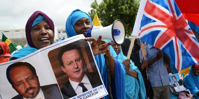 A Somali woman holds images of Britain's Prime Minister David Cameron and Somali President Hassan Sheikh Mohamud in Mogadishu, on May 7, 2013