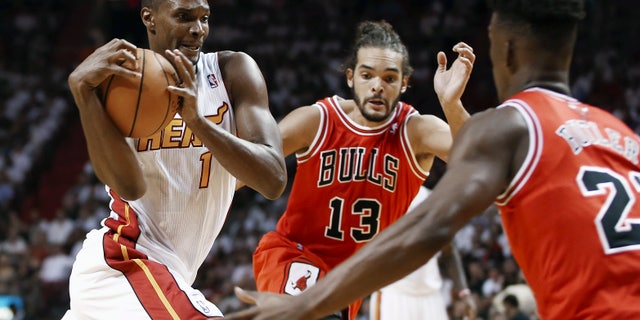 Miami Heat's Chris Bosh (1) tries to drive between Chicago Bulls' Joakim Noah (13) and Jimmy Butler (22) during the first half of an NBA basketball game in Miami, Tuesday, Oct. 29, 2013. (AP Photo/J Pat Carter)