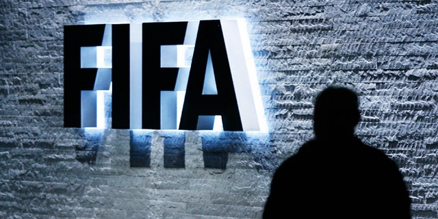 FILE - In this Oct. 29, 2007 file photo, a person stands next to the FIFA logo at the FIFA headquarter in Zurich, Switzerland. The Swiss Federal Office of Justice said six soccer officials have been arrested and detained pending extradition at the request of U.S. authorities ahead of the FIFA congress in Zurich. In a statement Wednesday, May 27, 2015, the FOJ said U.S. authorities suspect the officials of having received paid bribes totaling millions of dollars. (Steffen Schmidt/Keystone via AP, File)