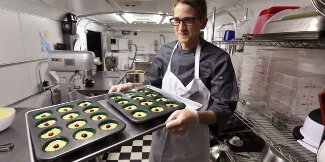 June 19, 2014: Chef Alex Tretter carries a tray of cannabis-infused peanut butter and jelly cups to the oven for baking at Sweet Grass Kitchen, a well-established Denver-based gourmet marijuana edibles bakery which sells its confections to retail outlets throughout the state.