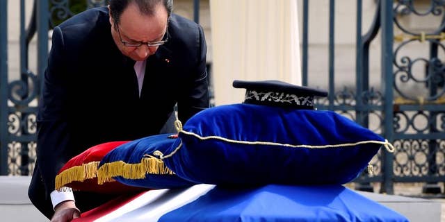 French President Francois Hollande pays his respects at the coffin of one the two police officials killed.