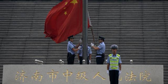 Police raise the Chinese flag outside the Intermediate People's Court in Jinan, Shandong Province on September 22, 2013