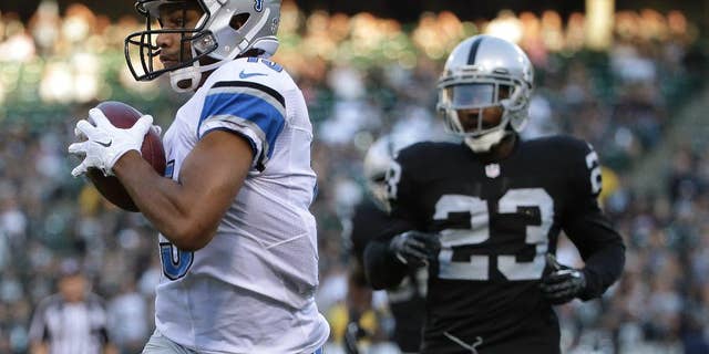 Detroit Lions wide receiver Golden Tate, left, scores on a 28-yard touchdown reception in front of Oakland Raiders cornerback Tarell Brown (23) during the first quarter of an NFL preseason football game in Oakland, Calif., Friday, Aug. 15, 2014. (AP Photo/Marcio Jose Sanchez)