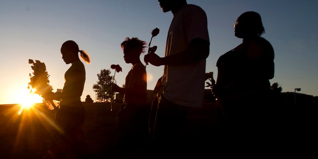 From left to right, 14-year-old Tylecia Amos, 15-year-old Shatyra Amos, 17-year-old Michael Walker, and 16-year-old Mykia Walker are carrying flowers to pose in front of a landmark monument in front of the Century Theater car park. Saturday, July 21, 2012 in Aurora, Colo. Twelve people were killed and dozens more injured during the Friday morning attack at the crowded theater during the screening of the Batman movie. 