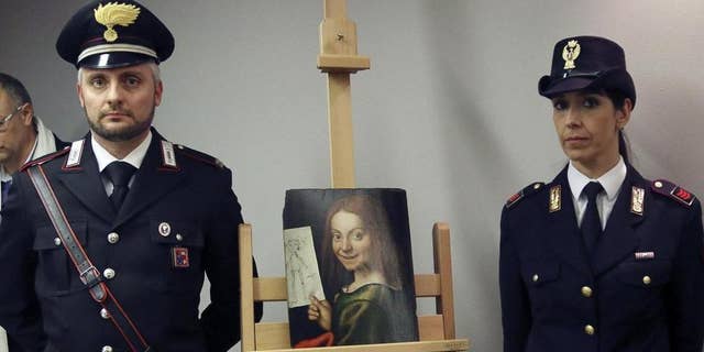 Carabinieri and police officers pose with one of the recovered paintings that were stolen from a Verona museum, at the Verona airport in Italy.