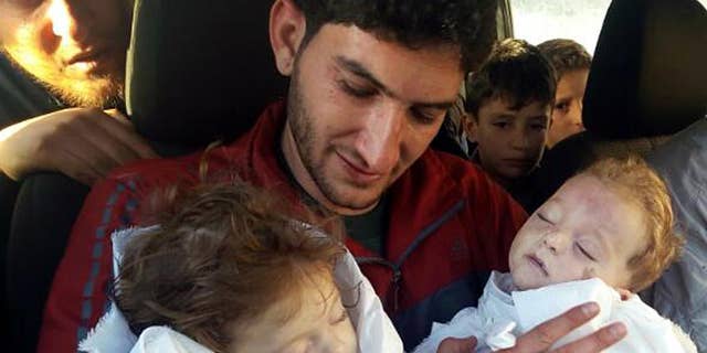 FILE - In this Tuesday, April 4, 2017, file photo, Abdul-Hamid Alyousef holds his twin babies who were killed by a chemical weapons attack, in Khan Sheikhoun in the northern province of Idlib, Syria. Alyousef also lost his wife, two brothers, nephews and many other family members in the attack that claimed scores of his relatives. New evidence presented by Human Rights Watch on Monday, May 1, indicates that the Syrian government used suspected nerve agents in four chemical weapons attacks since December including this one. (Alaa Alyousef via AP, File)