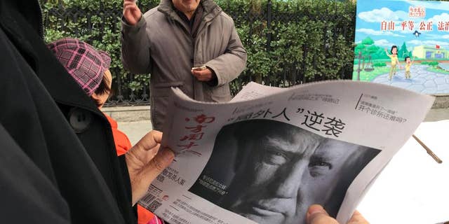 FILE - In this Nov. 10, 2016 file photo, a Chinese man holds up a Chinese newspaper with the front page photo of U.S. President-elect Donald Trump and the headline "Outsider counter attack" at a newsstand in Beijing, China. China views a Trump presidency with less trepidation. Citizens of China's capital Beijing on Saturday are expressing doubts about U.S. President Donald Trump's ability to steer the U.S. economy and manage China-American relations. (AP Photo/Ng Han Guan, File)