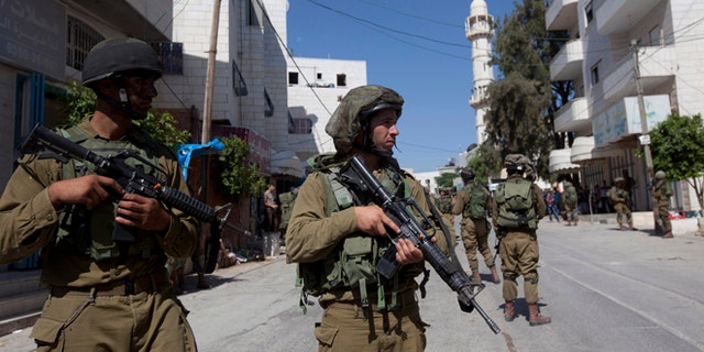 June 18, 2014: Israeli soldiers search for three missing Israeli teens believed to have been abducted in the West Bank, in the village of Taffouh near the West Bank city of Hebron. (AP/Majdi Mohammed)