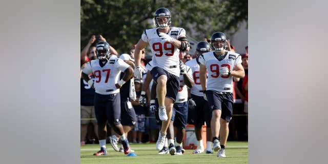 FILE - In this July 27, 2014 file photo, Houston Texans defensive end J.J. Watt (99) stretches with teammates during an NFL football training camp practice in Houston. Watt knows it's cliche to say "we're working hard every day" and he's "just trying to be a good teammate."(AP Photo/David J. Phillip, File)