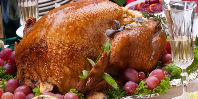 Garnished roasted turkey on Christmas decorated table with candles and flutes of champagne