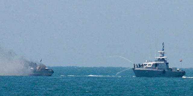 Egyptian navy vessel hoses down another which caught on fire at Mediterranean Sea Thursday, July 16, 2015. An Egyptian navy vessel caught fire off the coast of Sinai on Thursday after an exchange of gunshots with militants from the shore, the military said. (AP Photo/Eyad Baba)