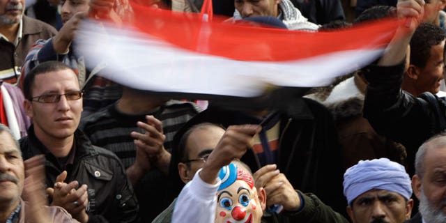 Dec. 1, 2011: An Egyptian waves a national flag while wearing a clown mask during a rally in support of the ruling supreme council of the armed forces, SCAF, at Abbasiya Square, in Cairo, Egypt.