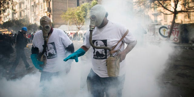 Nov. 23. 2011: Protesters attempt to get rid of a tear gas canister during clashes with Egyptian riot police, not pictured, near Tahrir square in Cairo, Egypt.