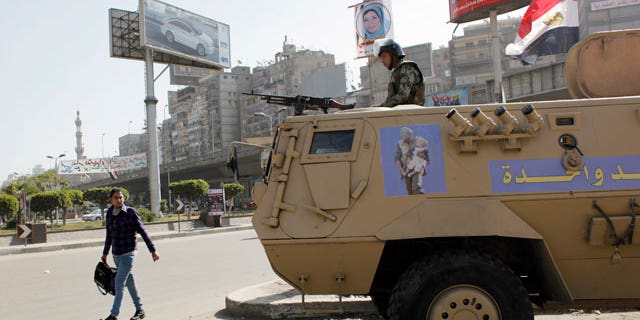 Feb. 11, 2012: An Egyptian man passes by an army patrol with a soldier on top of an armored vehicle flying the national flag and a sticker on the body with Arabic that reads "the army and the people are one hand," during a general strike in Cairo, Egypt.