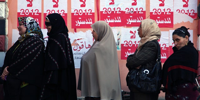 Dec. 22, 2012: Egyptian women line up outside a polling station next to stickers on a wall in Fayoum, about 62 miles south of Cairo, Egypt.