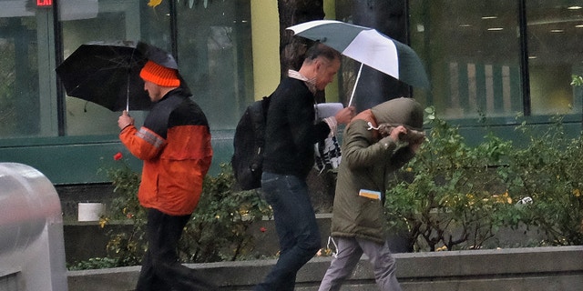 Pedestrians cover up from heavy El Nino rains in downtown Los Angeles.