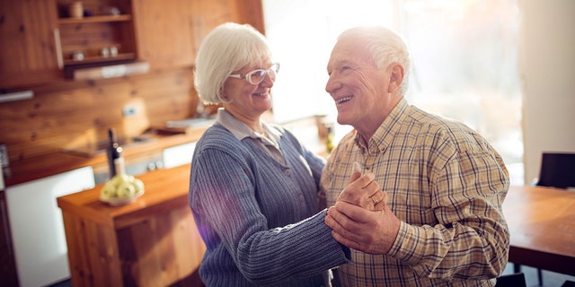 An elderly couple dancing in their kitchen.