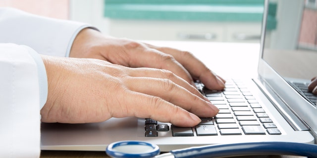 Κοντινό πλάνο του χεριού ενός γιατρού που πληκτρολογεί σε έναν υπολογιστή