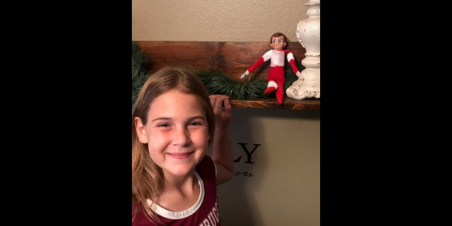Aubrie poses with her repaired Elf on the Shelf, "Sam."