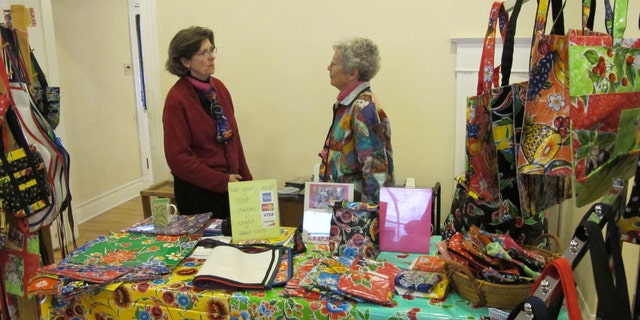 Polly Edmunds from Border Partners speaks with a fellow seller. Edmunds sells waterproof items made from Mexican oilcloth to benefit Palomas Oilcloth Designs.