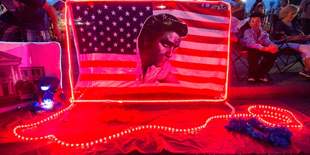 A street memorial is lit during a candlelight vigil for Elvis Presley in front of Graceland, Presley's Memphis home, on Tuesday, Aug. 15, 2017, in Memphis, Tenn. Fans from around the world are at Graceland for the 40th anniversary of his death. Presley died Aug. 16, 1977. (AP Photo/Brandon Dill)