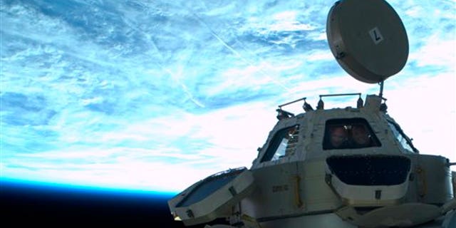 May 26: In this image provided by NASA astronauts Mike Kelly, left, and Ron Garan get their picture taken in the cupola window by astronaut Mike Fincke while he floats outside the International Space Station during the third spacewalk. (AP/NASA)