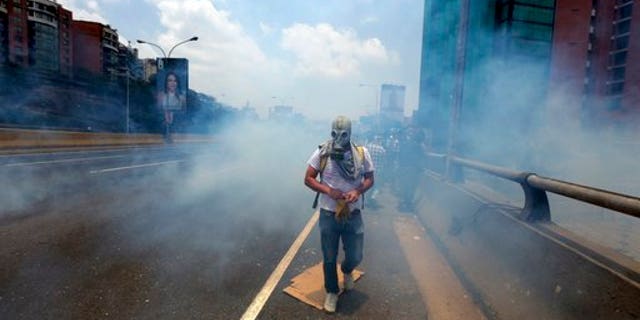 A demonstrator walks in the middle of a cloud of tear gas fired by the Bolivarian National Guard during a protest in Caracas, Venezuela, Monday, April 10, 2017.
