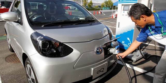 A participant to a press event by Toyota Motor Corp. puts a quick charger plug into the newly-developed compact electric vehicle "eQ" during a test drive at a press event in Tokyo Monday, Sept. 24, 2012. Toyota is boosting its green vehicle lineup, with plans for 21 new hybrids in the next three years, a new electric car later this year and a fuel cell vehicle by 2015 in response to growing demand for fuel efficient and environmentally friendly driving. (AP Photo/Koji Sasahara)