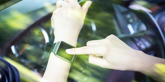 A woman uses smartwatch in the car. Smart watch concept.