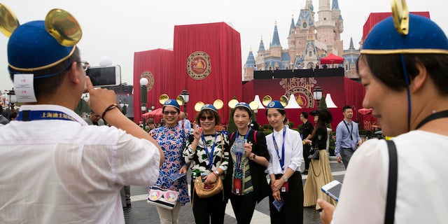 Guests strike pose on opening day at the newest Disney resort and theme park property in Shanghai, China.
