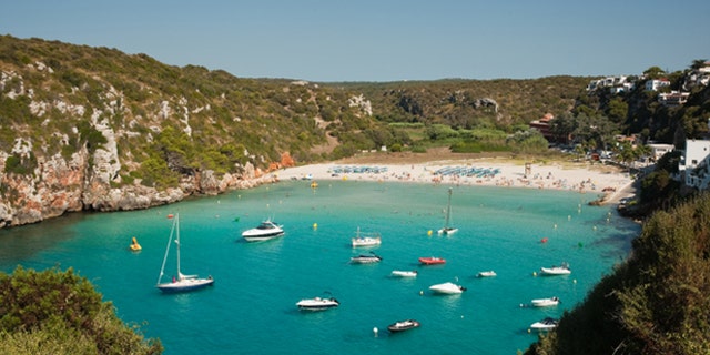 Beach on a bay with aqua water, several boats. Suitable for the summer holiday concept
