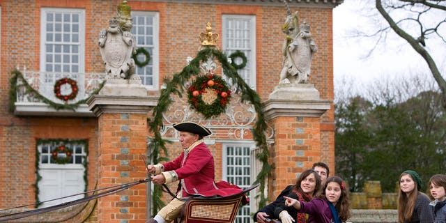 Model released visitors tour on Palace Green in an open carriage during the Christmas Season. Colonial Williamsburg's Historic Area.