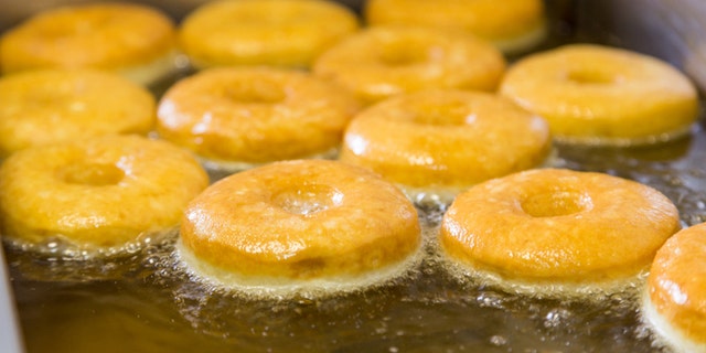 fried equal round doughnuts in deep-fryer on manufacture