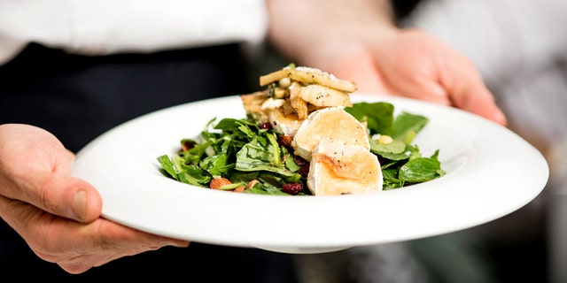 Chef holding a salad of roast goat cheese