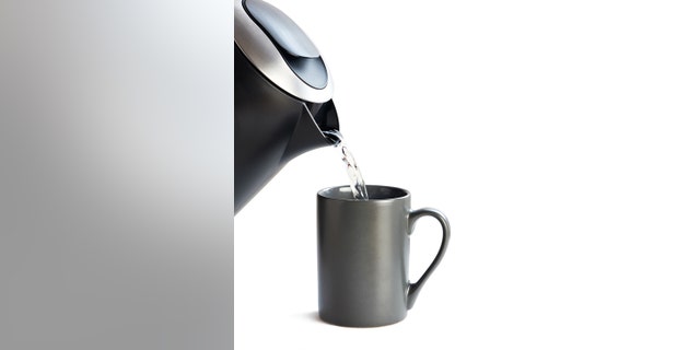 Modern kettle pouring water into a cup on a white background