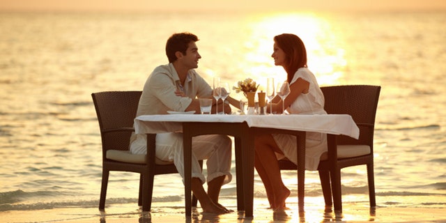 A young couple share a romantic dinner on the beach in the Maldives