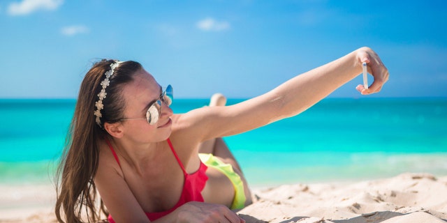 Beautiful woman taking a photo herself on tropical beach