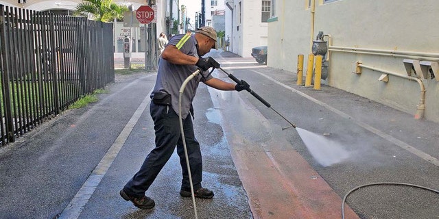 A worker washes down alleyways in Miami Beach. Travel insurer Allianz is predicting a 15 percent drop in Florida travel amid Americans' heightened fear of the Zika virus.