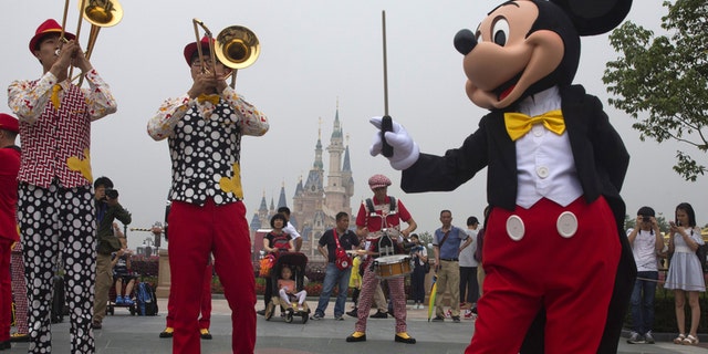 Mickey Mouse entertains onlookers on the rainy day opening of Shanghai Disney Resort.
